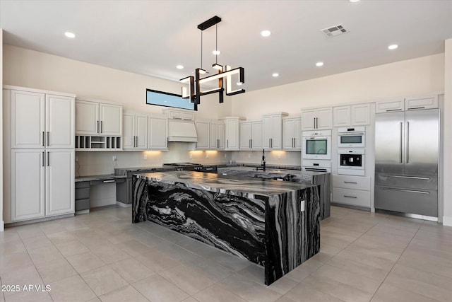 29215 N 136th St, Scottsdale, AZ 85262 - kitchen with built in refrigerator, white double oven, premium range hood, a chandelier, and decorative backsplash
