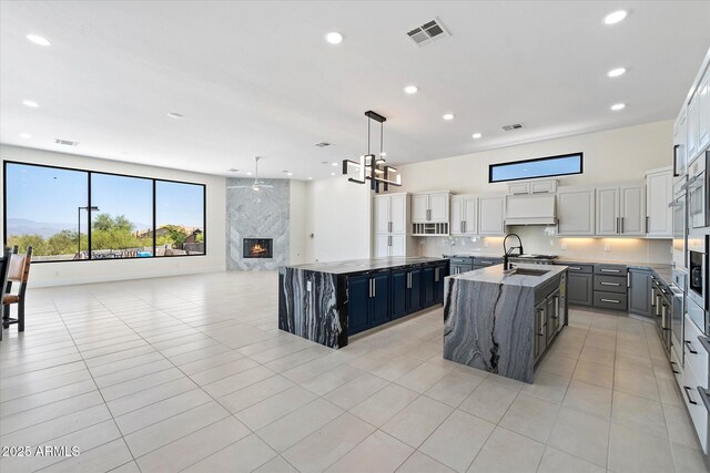29215 N 136th St, Scottsdale, AZ 85262 - kitchen with a large island with sink, a high end fireplace, recessed lighting, custom range hood, and stone counters