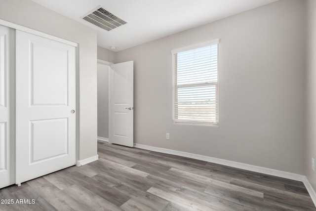 8208 W Albeniz Pl, Phoenix, AZ 85043 - unfurnished bedroom with baseboards, wood finished floors, and a closet