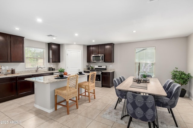 8208 W Albeniz Pl, Phoenix, AZ 85043 - kitchen with appliances with stainless steel finishes, a kitchen bar, light tile patterned floors, a kitchen island, and a sink