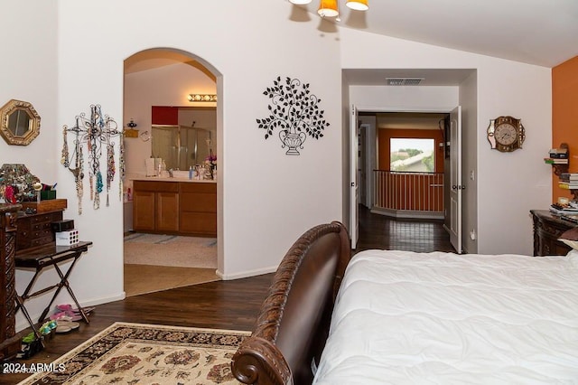 bedroom with ensuite bath, lofted ceiling, and dark hardwood / wood-style flooring