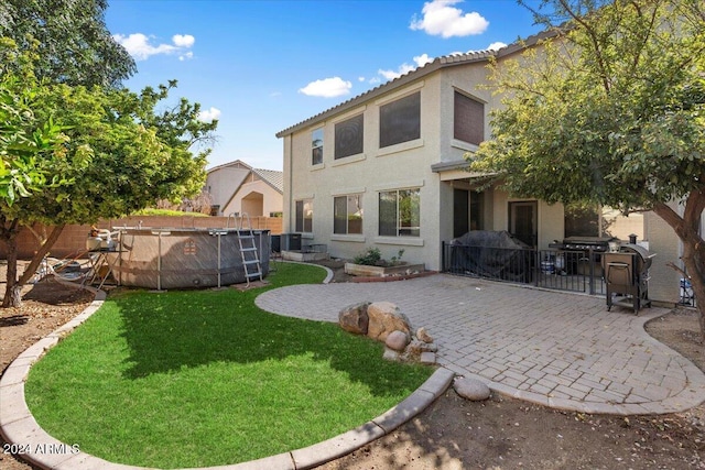 back of property featuring a yard, cooling unit, and a patio area