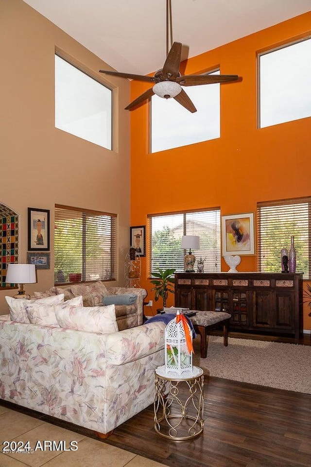 living room featuring ceiling fan, wood-type flooring, a wealth of natural light, and a high ceiling