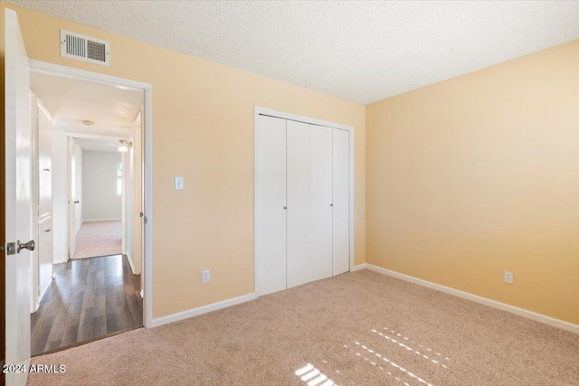 unfurnished bedroom featuring carpet floors, a textured ceiling, and a closet