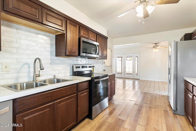 kitchen featuring french doors, sink, tasteful backsplash, light wood-type flooring, and appliances with stainless steel finishes