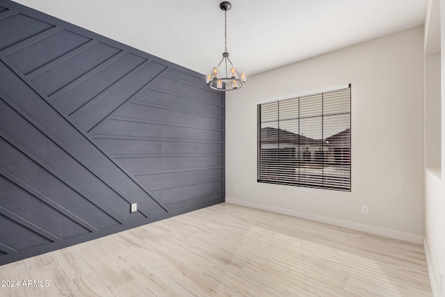 unfurnished room with a chandelier and light hardwood / wood-style floors