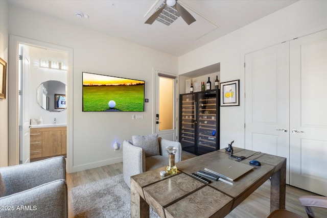 home office with light hardwood / wood-style floors, wine cooler, and ceiling fan