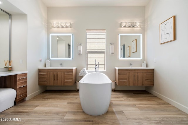 bathroom with a bath, vanity, and wood-type flooring