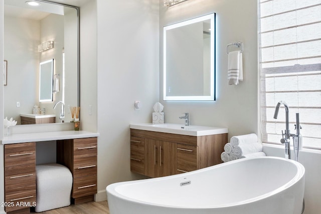 bathroom with vanity, wood-type flooring, and a bath