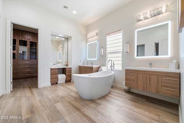 bathroom with hardwood / wood-style floors, vanity, and a tub to relax in