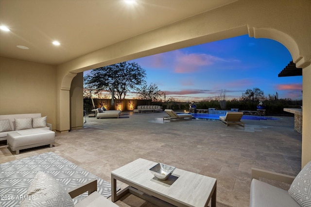 patio terrace at dusk with outdoor lounge area and a swimming pool