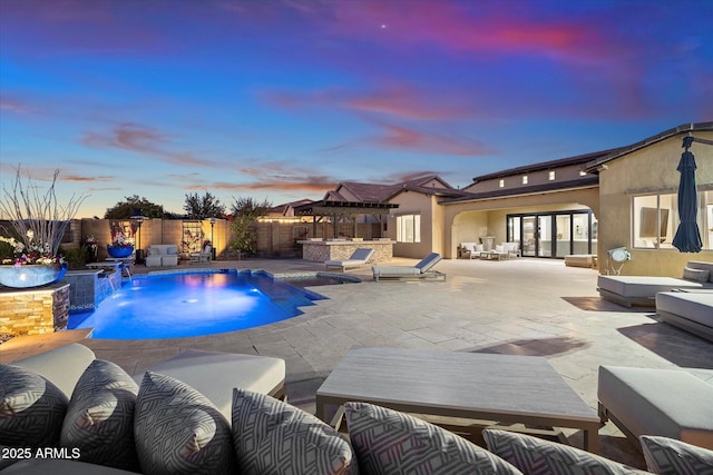 pool at dusk featuring pool water feature and a patio area