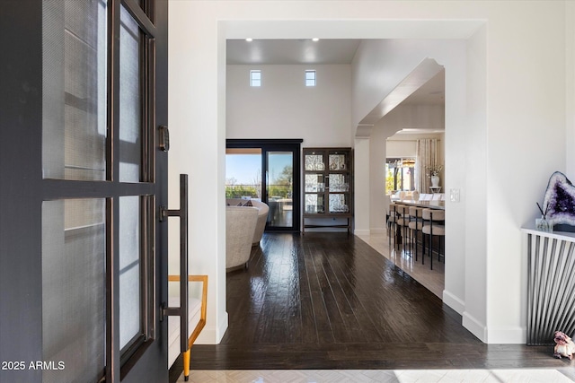 entryway with a towering ceiling, a healthy amount of sunlight, and wood-type flooring