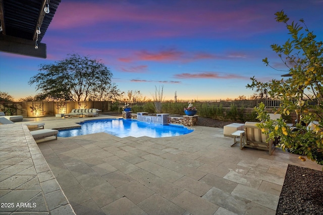 pool at dusk with pool water feature, a hot tub, and a patio area