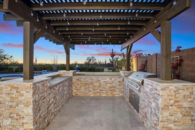 patio terrace at dusk with an outdoor kitchen, area for grilling, a pergola, and an outdoor bar