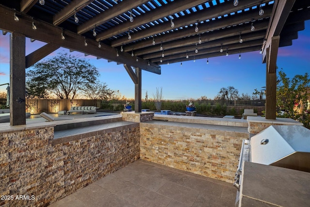 patio terrace at dusk with outdoor lounge area and an outdoor kitchen