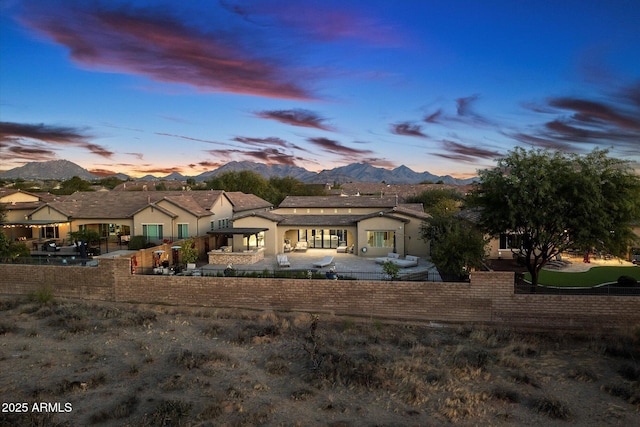 back house at dusk with a mountain view and a patio