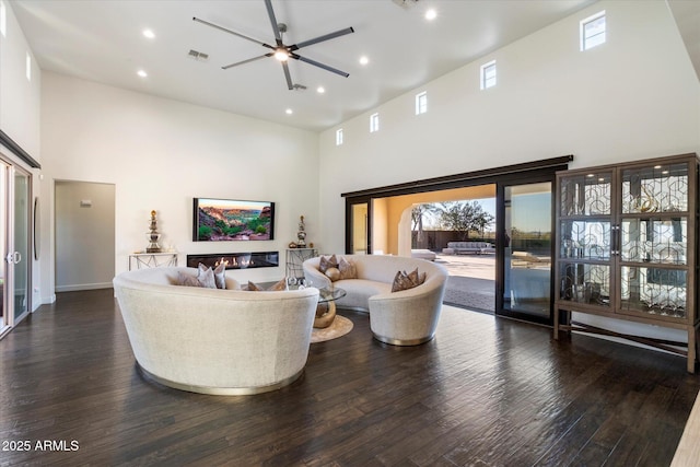 living room featuring a towering ceiling, dark hardwood / wood-style flooring, and ceiling fan