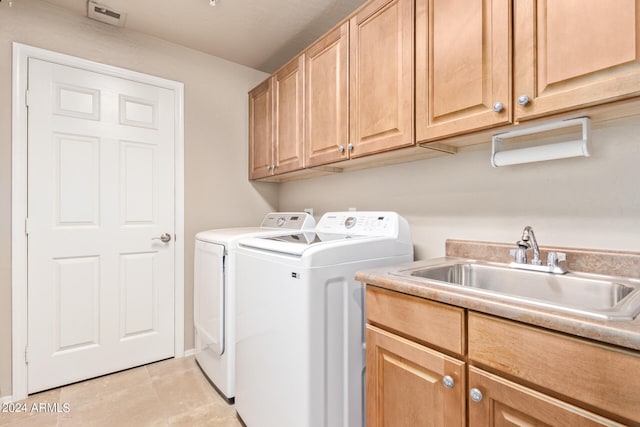 washroom with light tile patterned floors, cabinets, sink, and washing machine and clothes dryer