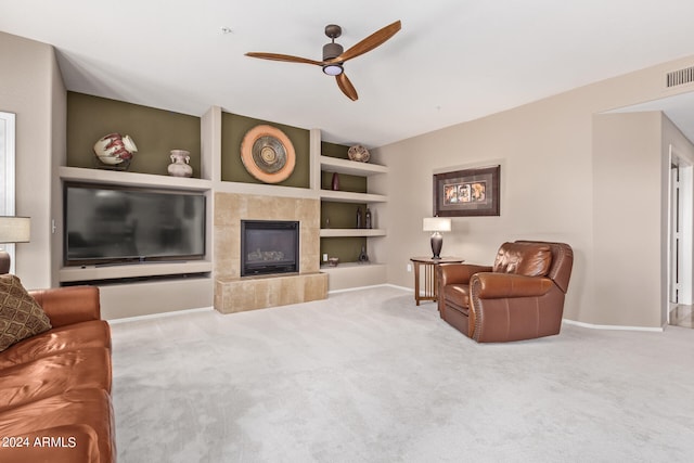 carpeted living room with ceiling fan, a fireplace, and built in shelves