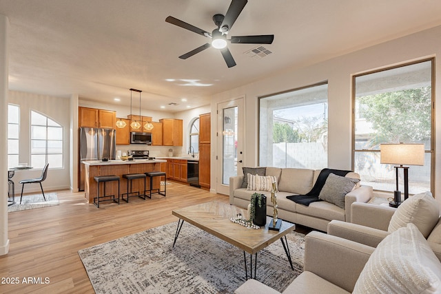 living room featuring a healthy amount of sunlight, sink, ceiling fan, and light hardwood / wood-style floors