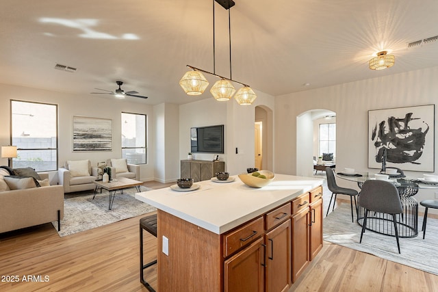 kitchen featuring pendant lighting, a kitchen breakfast bar, a center island, ceiling fan, and light hardwood / wood-style floors