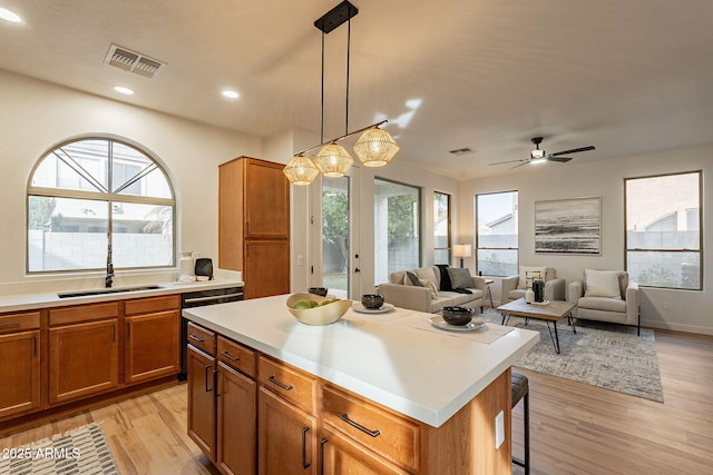 kitchen with sink, light hardwood / wood-style flooring, hanging light fixtures, a kitchen breakfast bar, and a center island