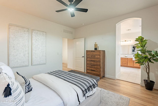 bedroom featuring connected bathroom, light hardwood / wood-style flooring, and ceiling fan