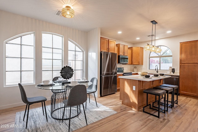 kitchen with hanging light fixtures, light hardwood / wood-style flooring, black appliances, and a center island