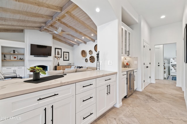 kitchen featuring lofted ceiling with beams, light stone countertops, wood ceiling, white cabinets, and beverage cooler