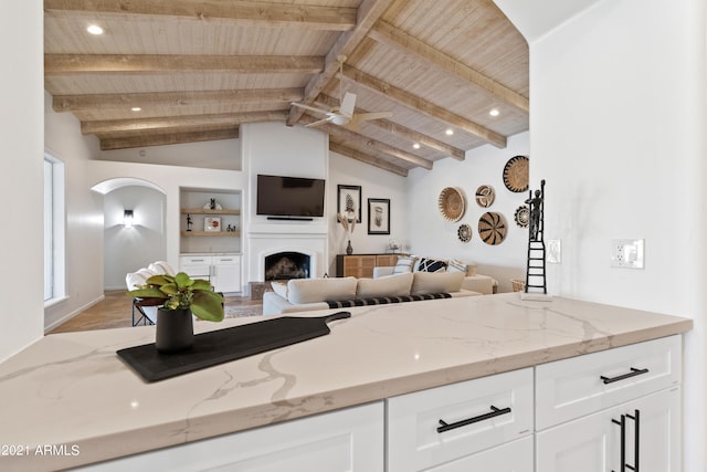 kitchen featuring vaulted ceiling with beams, white cabinets, light hardwood / wood-style flooring, wooden ceiling, and light stone countertops