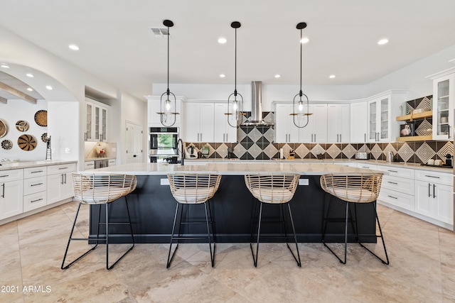 kitchen with extractor fan, decorative light fixtures, a breakfast bar, and a spacious island