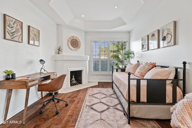 bedroom with wood-type flooring and a raised ceiling