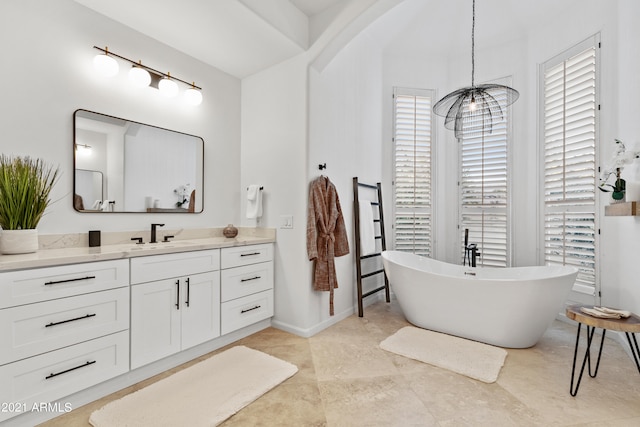 bathroom featuring plenty of natural light, a chandelier, a tub to relax in, and vanity