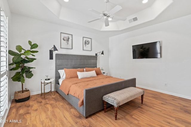 bedroom featuring ceiling fan, hardwood / wood-style flooring, and a raised ceiling