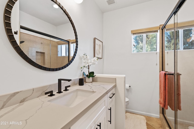 bathroom with toilet, an enclosed shower, and vanity