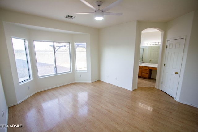 spare room featuring built in desk, light hardwood / wood-style floors, and ceiling fan