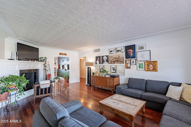 living room with dark hardwood / wood-style floors, ornamental molding, a fireplace, and a textured ceiling