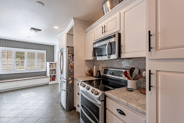 kitchen with white cabinetry, light stone counters, and stainless steel appliances