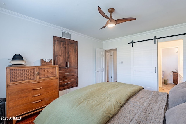 bedroom with connected bathroom, crown molding, hardwood / wood-style flooring, ceiling fan, and a barn door