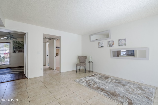 spare room with light tile patterned floors, a textured ceiling, and ceiling fan