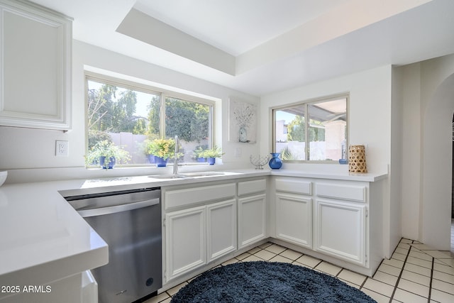 kitchen with white cabinetry, sink, light tile patterned floors, and stainless steel dishwasher