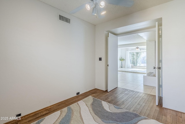 bedroom with ceiling fan, a textured ceiling, and light wood-type flooring