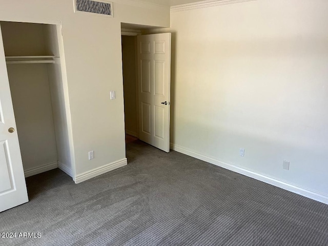 unfurnished bedroom with crown molding, a closet, and dark carpet