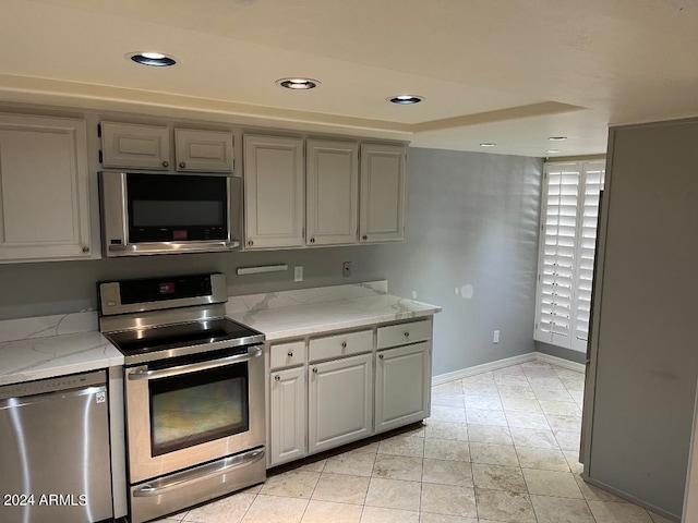 kitchen with gray cabinets, light stone counters, and stainless steel appliances