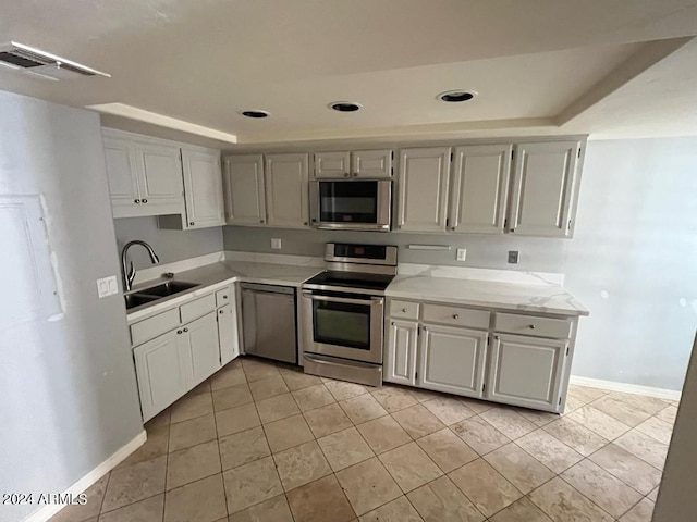 kitchen featuring a raised ceiling, sink, light tile patterned flooring, and stainless steel appliances