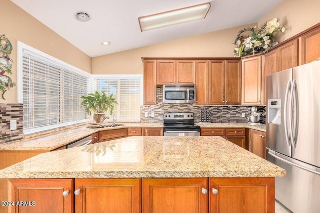 kitchen with appliances with stainless steel finishes, light stone counters, vaulted ceiling, and sink