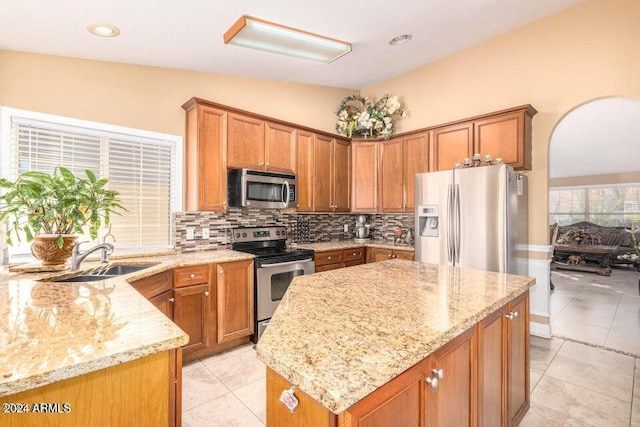 kitchen featuring sink, light stone counters, lofted ceiling, light tile patterned flooring, and appliances with stainless steel finishes