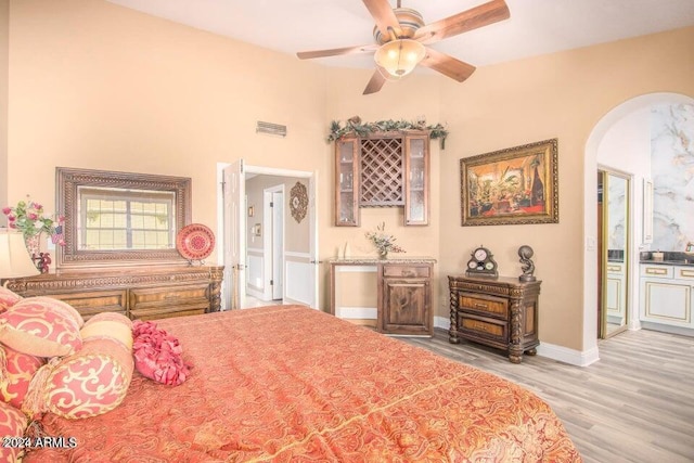 bedroom featuring ceiling fan, a wood stove, and light hardwood / wood-style flooring