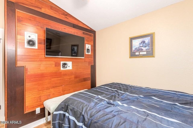 bedroom featuring wooden walls and vaulted ceiling